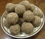 A plate of millet snacks, each shaped into a round ball, presented on a ceramic plate with gold trim.